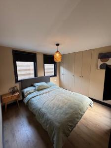 a bedroom with a large bed and a pendant light at Family holiday home by beach and forest in Dirkshorn