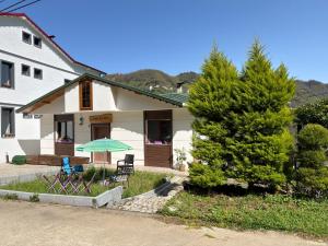 a white house with a tree and chairs and an umbrella at Konak village housee in Ardeşen