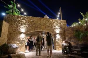 a group of people standing outside of a stone wall at night at Stenakas Apartments in Chios
