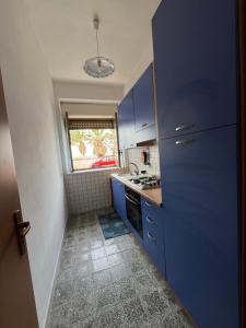 a small kitchen with blue cabinets and a window at La casa del professore libeccio in Nicotera Marina