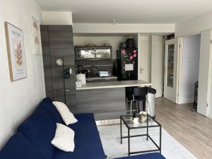 a living room with a blue couch and a counter at Patty Home Stay in Carrières-sous-Poissy