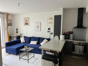 a living room with a blue couch and a table at Patty Home Stay in Carrières-sous-Poissy