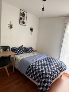 a bedroom with a bed and a table and a desk at Patty Home Stay in Carrières-sous-Poissy