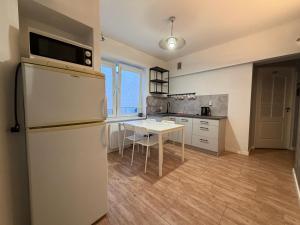 a kitchen with a white refrigerator and a table at Host-X Pokoje Ciche Centrum Mała Sienkiewicza -fv in Kielce