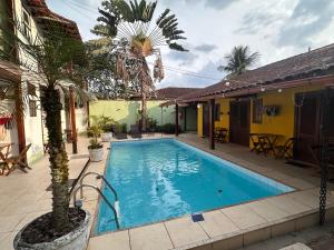 a pool with a palm tree next to a house at Pousada Acquarela Paraty -a 450 mts do centro historico! we also speak English in Paraty