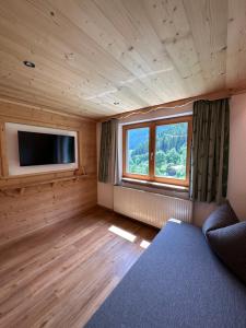 a room with a bed and a tv and a window at Apart Alpenpension Maderer in Gaschurn