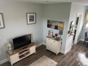 a living room with a flat screen tv on a white wall at Atlantic way Apartment 1 in Breaghwy