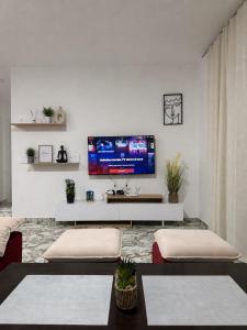 a living room with two tables and a tv on a wall at Sol & Sea Apartments in Shëngjin