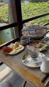 a table with plates and bowls of food on it at Pousada Acquarela Paraty -a 450 mts do centro historico! we also speak English in Paraty