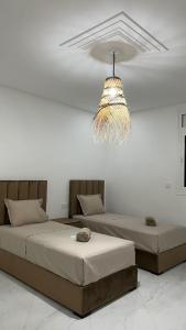 two beds in a room with a chandelier at Villa Raha in Selouane