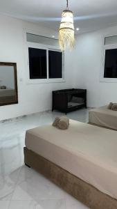 a white bedroom with two beds and a chandelier at Villa Raha in Selouane