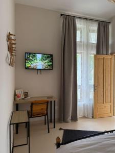 a bedroom with a desk and a television on the wall at Porta E Gjelbër in Përmet