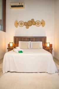 a bedroom with a large white bed with two lights at Pousada Gauleses - Refugio de Charme na Praia do Rosa by La Vem Férias in Praia do Rosa
