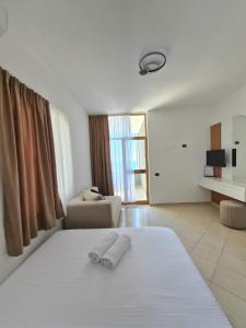 a bedroom with a white bed and a couch and a window at Eden Hotel in Shëngjin