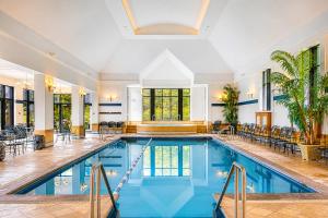 a pool in a hotel with chairs and tables at Villa Experience Nature Le Nid in Saint-Irénée