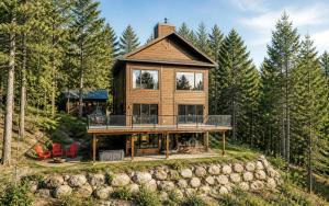 a log cabin in the woods with a large deck at Villa Experience Nature Le Nid in Saint-Irénée