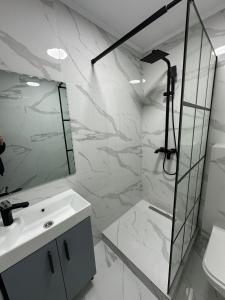 a white bathroom with a shower and a sink at Renovat si stilat pentru un sejur de exceptie in Ungheni