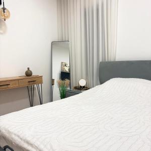 a bedroom with a white bed and a mirror at Geron's וילת אירוח in Bet Sheʼan +24 photos