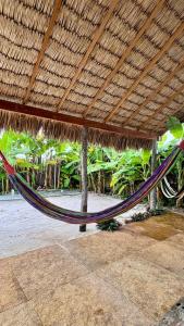a hammock under a straw roof on a beach at Varanda das Dunas in Santo Amaro