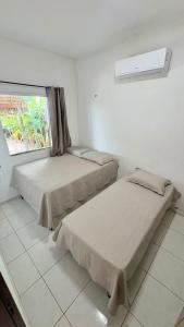 two beds in a white room with a window at Varanda das Dunas in Santo Amaro