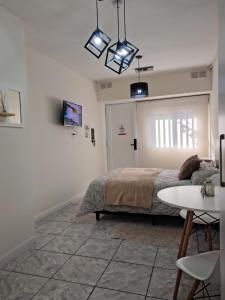 a white bedroom with a bed and a table at Moderno Estudio PB - Entrada Autónoma, Equipado y Cerca de Todo in Mendoza