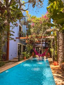 a swimming pool with a waterfall in a garden at Le Muuch Hotel Boutique in Valladolid