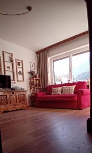 a living room with a red couch and a window at La Sibilla in Riscone +26 photos