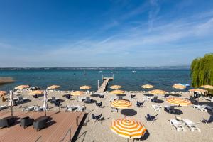 a beach with chairs and umbrellas and a pier at Hotel Tre Vele in Sirmione +128 photos