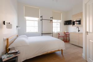 a white bedroom with a bed and a kitchen at Check In Belfast in Belfast