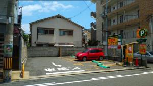 a red car parked in a parking lot next to a building at Osaka03 地铁站步行两分钟 直达难波 日本桥 梅田 关西机场 in Osaka