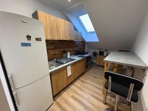 a kitchen with a white refrigerator and a table at Attic Apartment in Kočovce