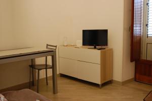 a room with a tv on a dresser with a desk at La Dimora Sicula in Modica