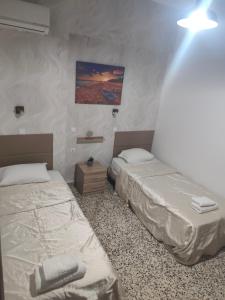two twin beds in a room with a light at Garden Studios N3 in Archangelos