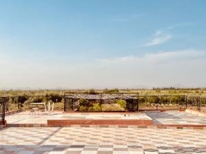 a patio with a fence and a table and benches at Marrakech ferme lodge in Marrakesh