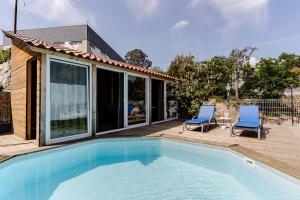 a swimming pool with two chairs and a house at Casa entre Rios in Alpendurada