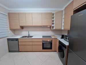 a kitchen with wooden cabinets and a stainless steel refrigerator at Cabanas Family Apartment in Cabanas de Tavira