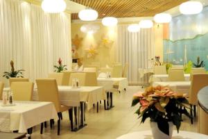 restauracja z białymi stołami, krzesłami i kwiatami w obiekcie Falken am Rotsee w Lucernie