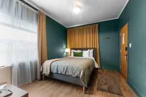 ein Schlafzimmer mit einem Bett und einer grünen Wand in der Unterkunft Balmoral Hotel in Barrys Bay
