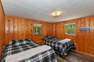 two beds in a room with wooden walls at Applewood Cabins & Guest Cabin Near the Village in Big Bear Lake