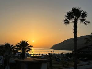 a sunset over a beach with palm trees and the ocean at La casa del professore libeccio in Nicotera Marina +2 photos