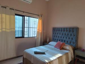 a bedroom with a bed with a blue headboard and a window at Finca la Esperanza in Guadalupe