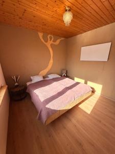 a bedroom with a bed with a tree on the wall at Das Haus am See - der idyllische Privatsee nahe Wien in Tulln