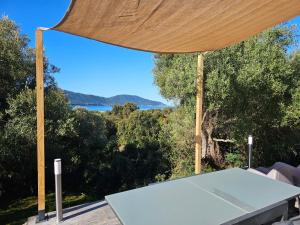 a table under a large umbrella with a view of the ocean at Yourte Corsica vera in Appietto