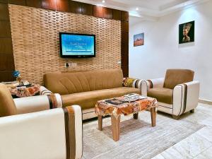 a living room with a couch and two chairs and a tv at Arte Pyramids Hotel in Cairo