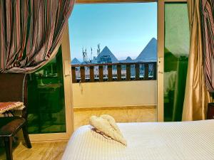 a bedroom with a bed and a balcony with a view at Arte Pyramids Hotel in Cairo
