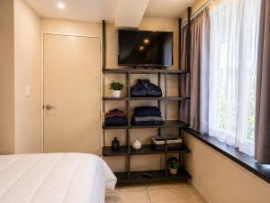 a bedroom with a bed and a tv on a shelf at Habitación individual con baño privado a 3 Min del Estadio Azteca-Banorte y muy cerca de zona de hospitales in Mexico City
