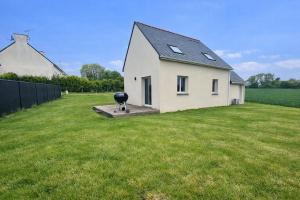 a small white house with a large grass yard at Kougou Ruz in Audierne