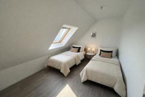 a attic bedroom with two beds and a window at Kougou Ruz in Audierne