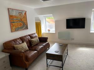 a living room with a brown leather couch and a coffee table at Ladysmith Guest House in Ullapool