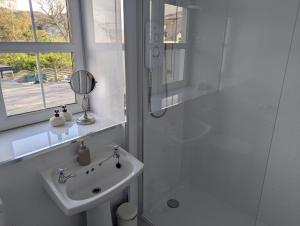 a white bathroom with a sink and a shower at Ladysmith Guest House in Ullapool +11 photos